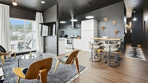 Un espacio habitable moderno con comedor, cocina y un amplio ventanal con vistas a un área de estar al aire libre.