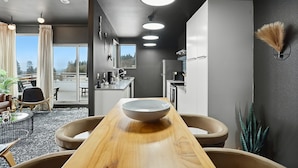 Una cocina moderna con una isla central, un comedor con mesa de madera y vistas al exterior.