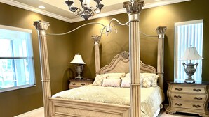 A four-poster bed with ornate columns, a nightstand with a lamp, and a dresser with drawers. - Vacation Home In West Palm beach (WEST PALM BEACH)