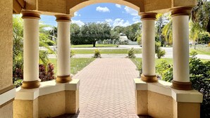 A covered walkway with columns, leading to a grassy area with a clear sky. - Vacation Home In West Palm beach (WEST PALM BEACH)