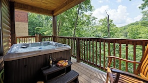Un jacuzzi en una terraza de madera con vistas a un bosque.