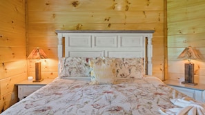 Una habitación de madera con una cama, dos mesitas de noche y lámparas.