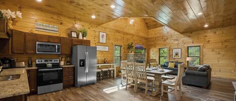 A spacious kitchen with modern appliances, a dining area with wooden furniture, and a cozy living space with a fireplace.