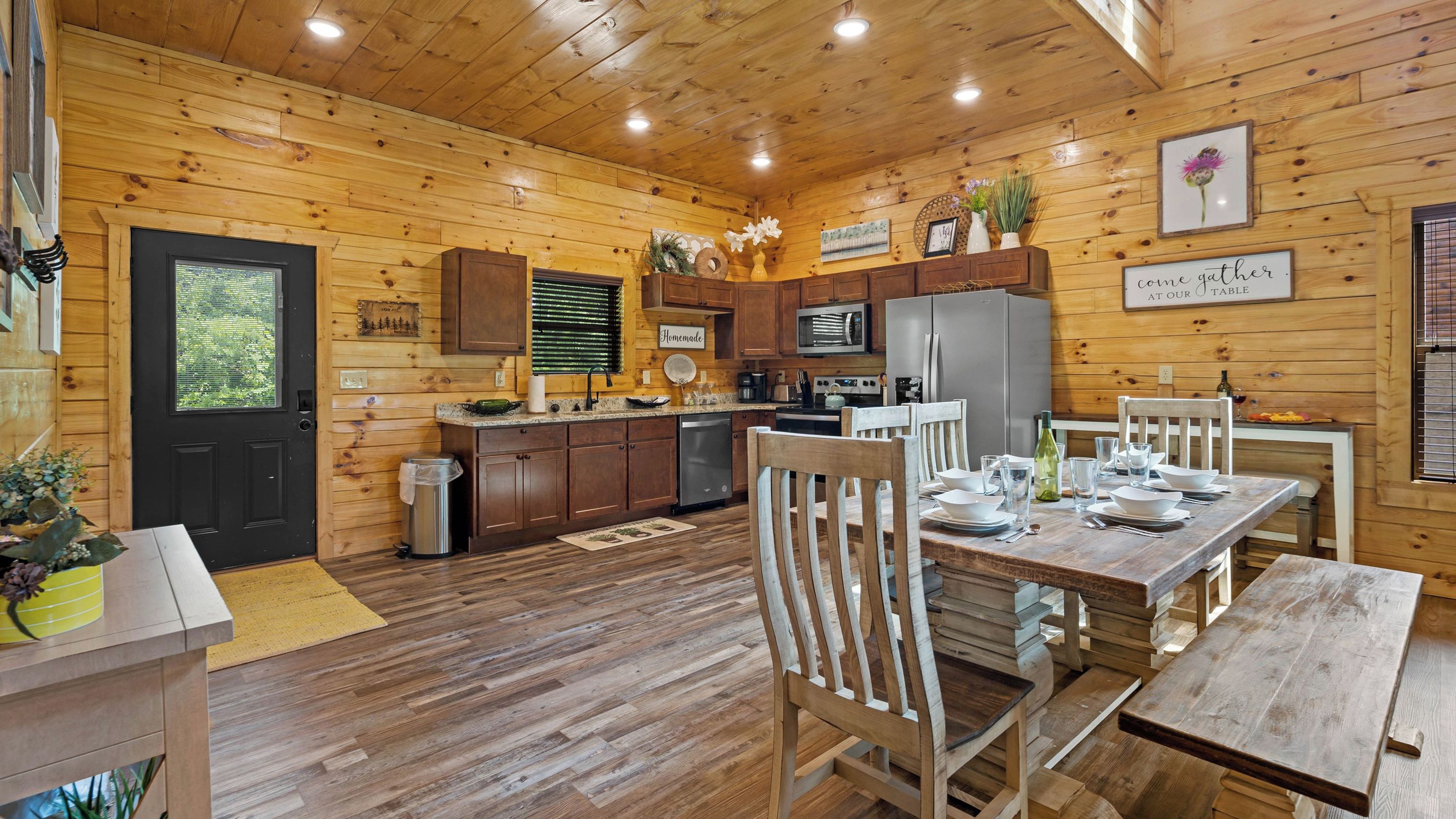 Una cabaña de madera con comedor, cocina y una puerta negra.