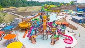 A water park with multiple slides and water features, surrounded by a parking area and a pool.