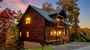 A log cabin with a balcony, a porch, and a chimney.