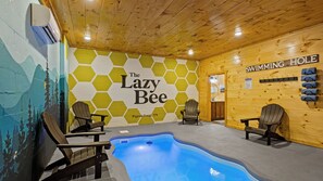 A pool area with hexagonal wall art, Adirondack chairs, and a sign reading 'SWIMMING HOLE'.