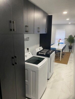 Compact laundry room with a front-loading washer and dryer, plus a small dining area with a table and chairs.