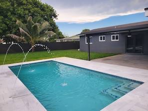 A rectangular swimming pool with clear blue water, surrounded by a tiled deck.