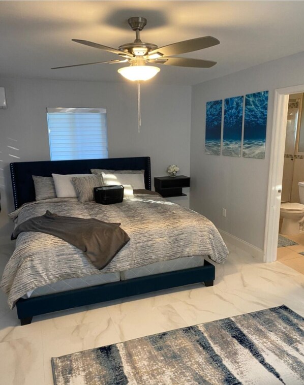 Relax in this serene bedroom with a large bed, ceiling fan, and bathroom.