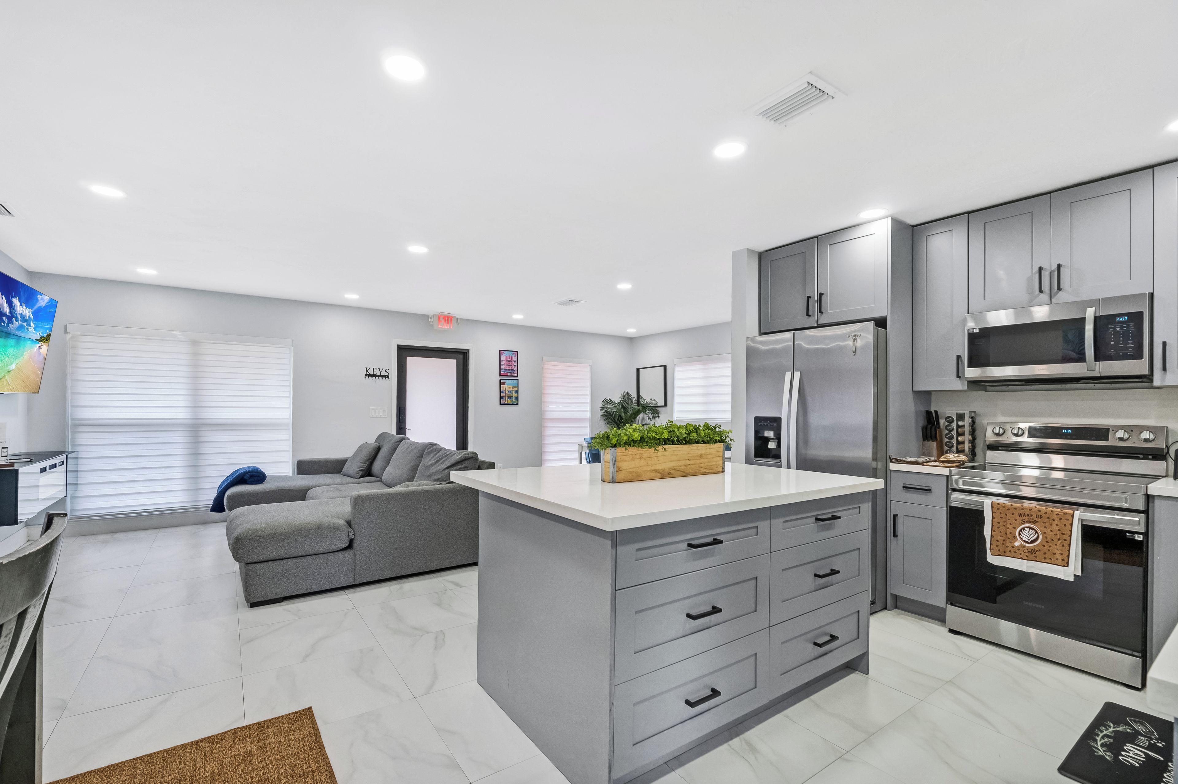 A modern kitchen with grey cabinetry, stainless steel appliances, and a central island with drawers.