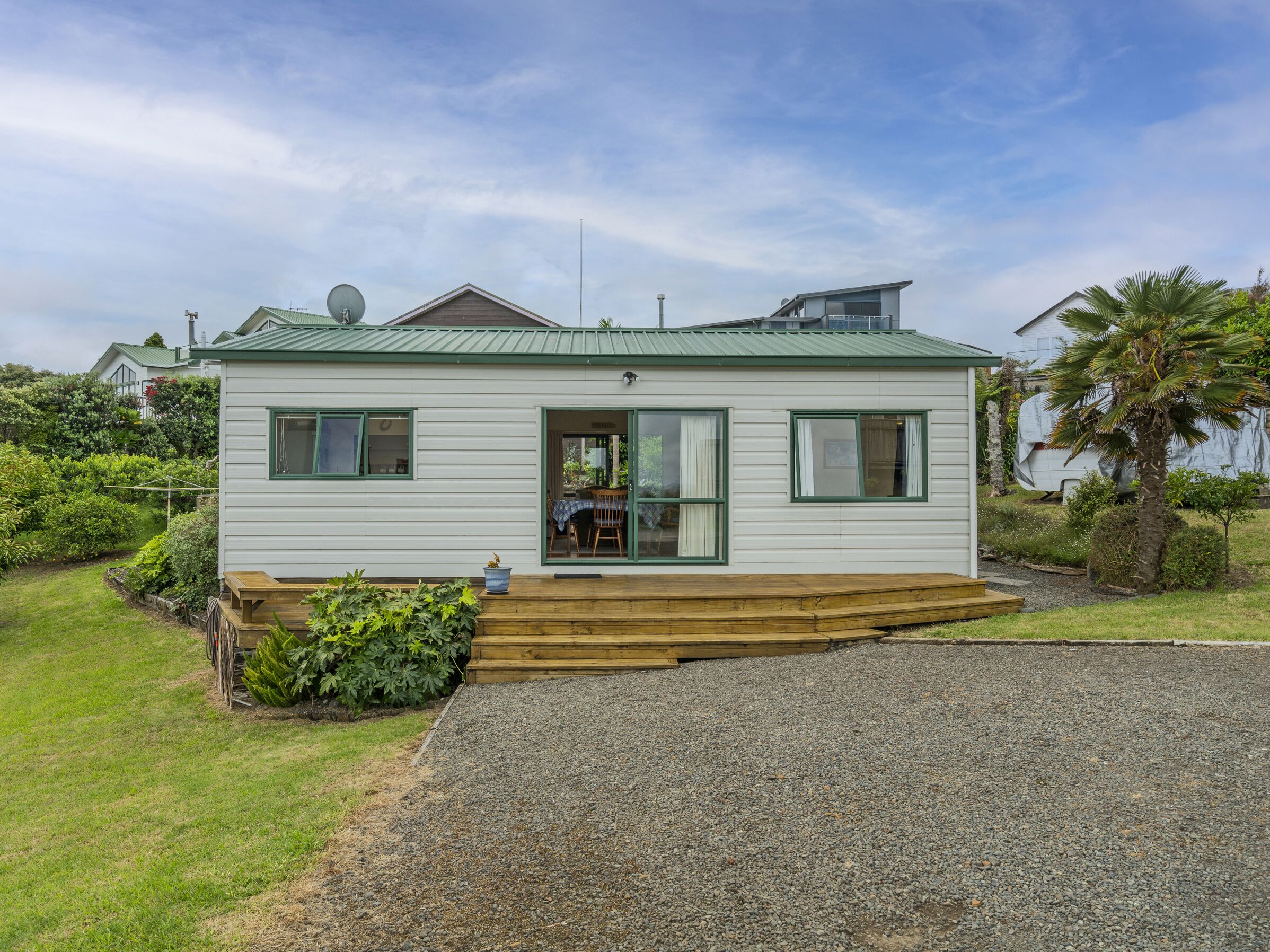 A single-story house with a front porch, a satellite dish, and a gravel driveway.
