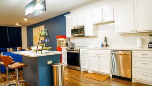 A modern kitchen with white cabinets, stainless steel appliances, and a blue accent wall. - 4 BR , Large Yard with HOT TUB, Fire pit,Basket ball hoop (Dallas)