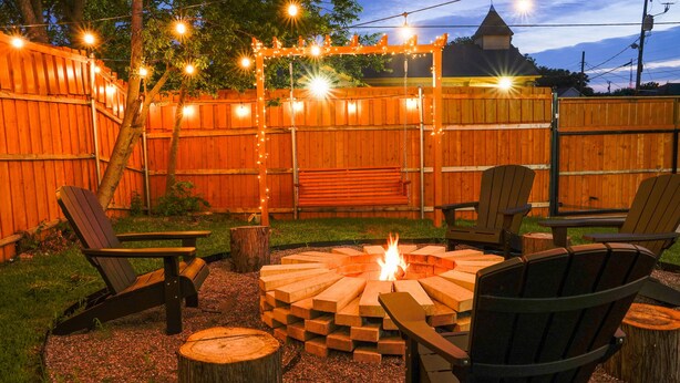 A backyard with a wooden fence, a fire pit, and Adirondack chairs. - 4 BR , Large Yard with HOT TUB, Fire pit,Basket ball hoop (Dallas)