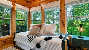 A wooden cabin bedroom with a bed, pillows, and a nightstand. - Close 2 Parkway|Family & Dog Retreat|Game Room (Sevierville)
