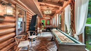 A wooden log cabin interior with a herringbone floor, wooden chairs, a foosball table, and a glass-top table with numbers. - Close 2 Parkway|Family & Dog Retreat|Game Room (Sevierville)