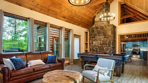 A cozy living room with a brown leather sofa, a pool table, and a stone fireplace. - Close 2 Parkway|Family & Dog Retreat|Game Room (Sevierville)