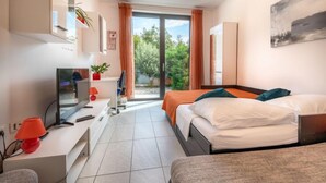 Quarto de hotel moderno com cama, escrivaninha, televisão e uma grande janela com vista para o verde.