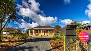 A holiday home rental with a covered porch, a fenced yard, and a clear sky. - The Lazy Carrot - Ohakune Holiday Home (Ohakune)