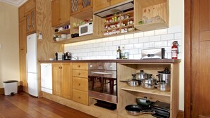 A kitchen with wooden cabinets, a microwave, a stove, and various kitchen utensils. - The Lazy Carrot - Ohakune Holiday Home (Ohakune)