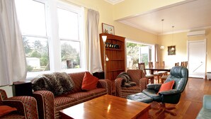 A spacious living room with a wooden coffee table, patterned sofas, and a leather armchair. - The Lazy Carrot - Ohakune Holiday Home (Ohakune)