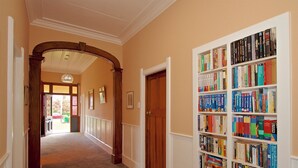A hallway with a bookshelf filled with books, a wooden door, and a carpeted floor. - The Lazy Carrot - Ohakune Holiday Home (Ohakune)
