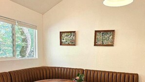 Uma área de refeições com uma mesa redonda de madeira, dois assentos acolchoados e um candelabro.