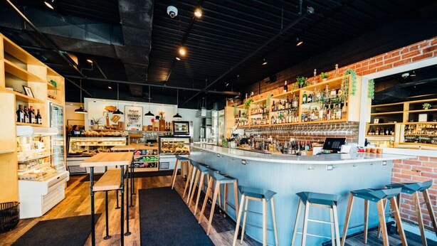 A bar with a long counter, stools, and shelves stocked with bottles. - One Of A Kind Huge Loft Minutes From Downtown (Detroit)