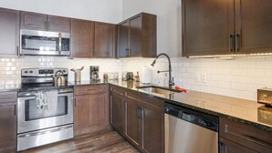 A modern kitchen with stainless steel appliances, wooden cabinets, and a tiled backsplash. - One Of A Kind Huge Loft Minutes From Downtown (Detroit)