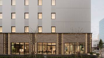 A modern hotel with a two-story structure, large windows, and a well-lit entrance area.
