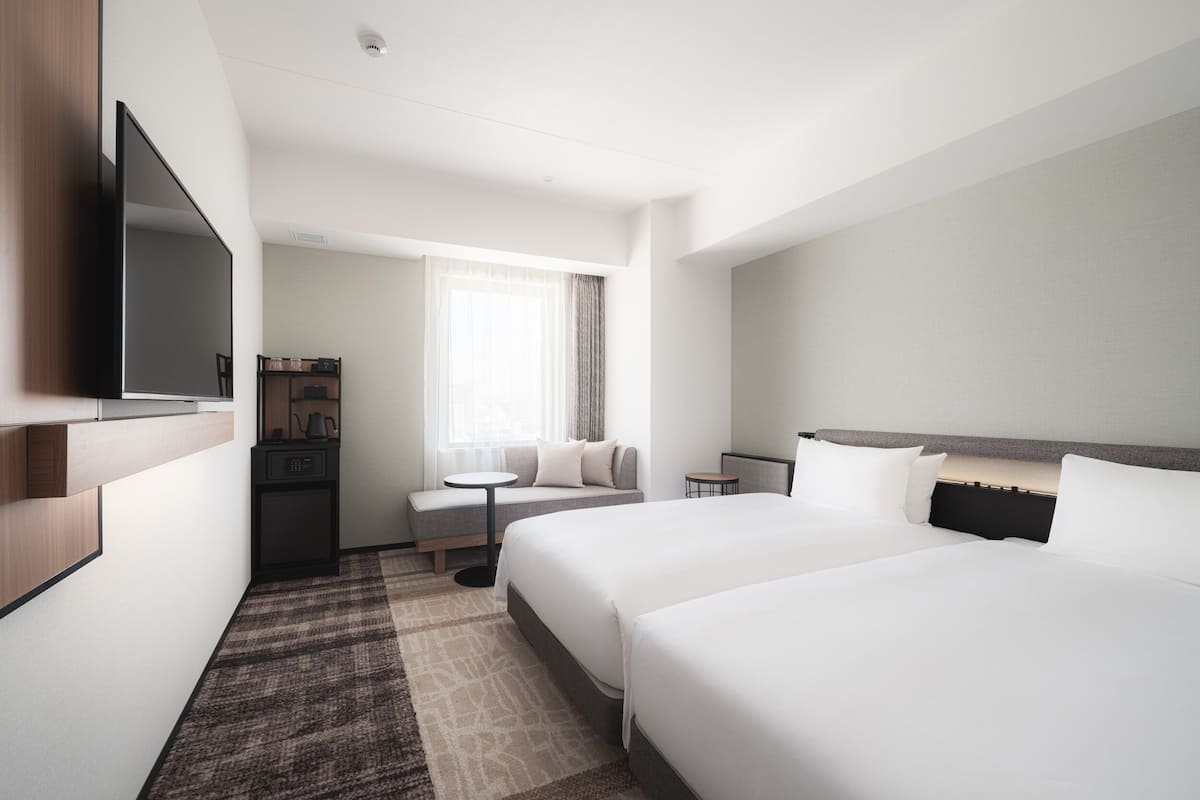 Een hotelkamer met twee bedden, een televisie, een klein tafeltje en een zithoek.