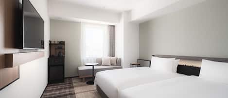 Habitación de hotel con dos camas, un televisor, una mesita y un sofá.