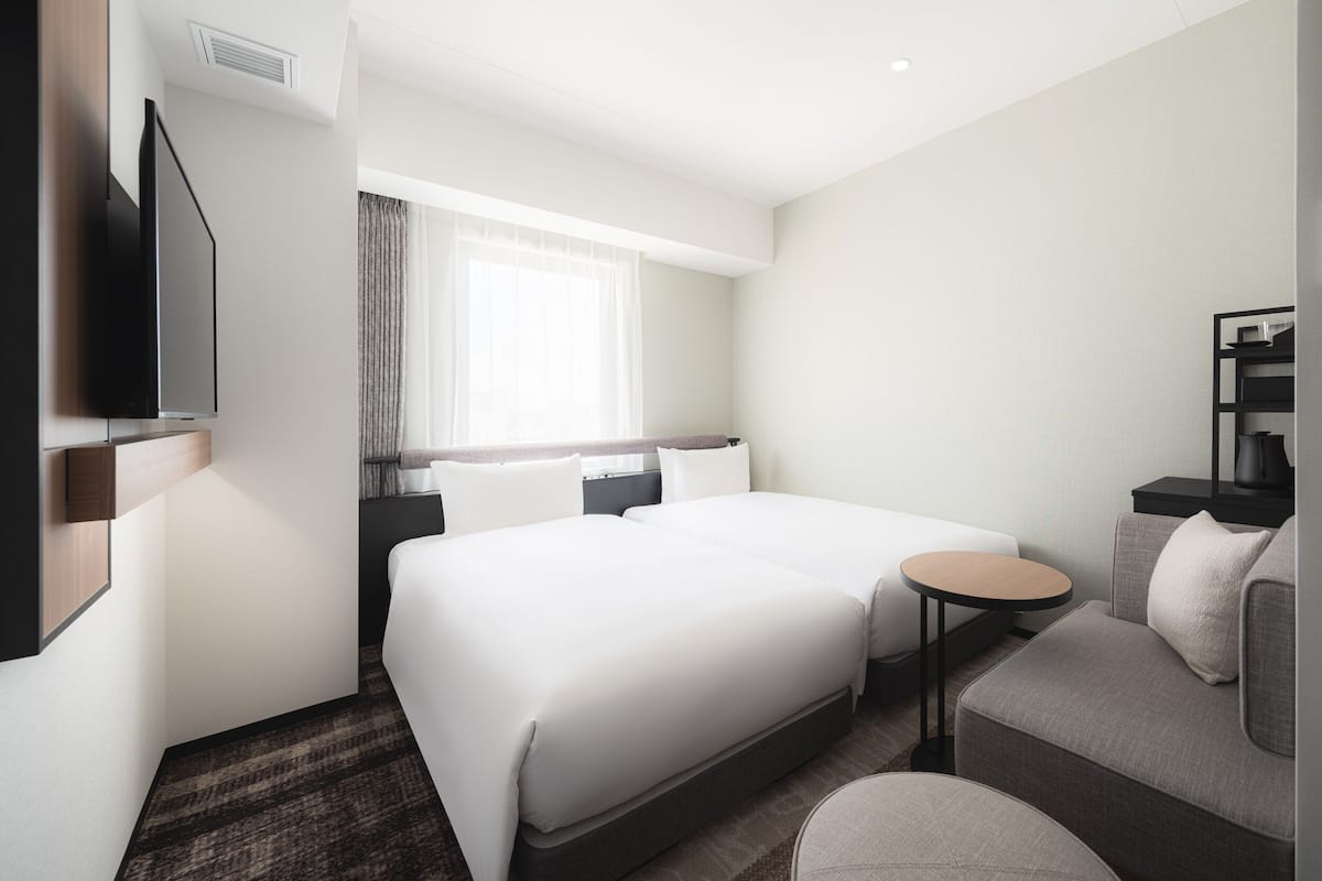 Een hotelkamer met een bed, een slaapbank, een televisie en een klein tafeltje.