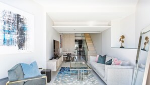 Ein modernes Wohnzimmer mit einer Couch, einem Couchtisch und einem Essbereich mit einem Glastisch und Stühlen.