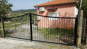 Eine von einer Mauer umgebete Anlage mit einem rosafarbenen Gebäude, einem Metallgittertor und Blick auf eine hügelige Landschaft.