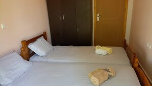 Ein Zimmer mit zwei Betten, einem Kleiderschrank und einer Tür.