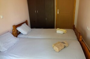 Quarto com duas camas, um guarda-roupa e uma porta.