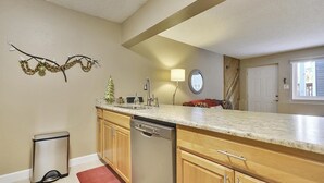 A kitchen with wooden cabinets, a dishwasher, a sink, and a small Christmas tree. - Main Street Snowcave walkable to Quicksilver (Breckenridge)