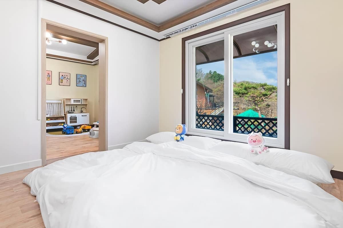 Ein Schlafzimmer mit einem großen Fenster, einem Bett und Blick auf einen Garten.