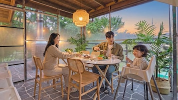 A dining area with a round table, chairs, and a hanging light fixture.
