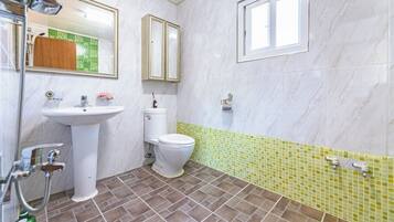 A bathroom with a white sink, a toilet, and a shower. There are two mirrors above the sink and a window above the toilet.