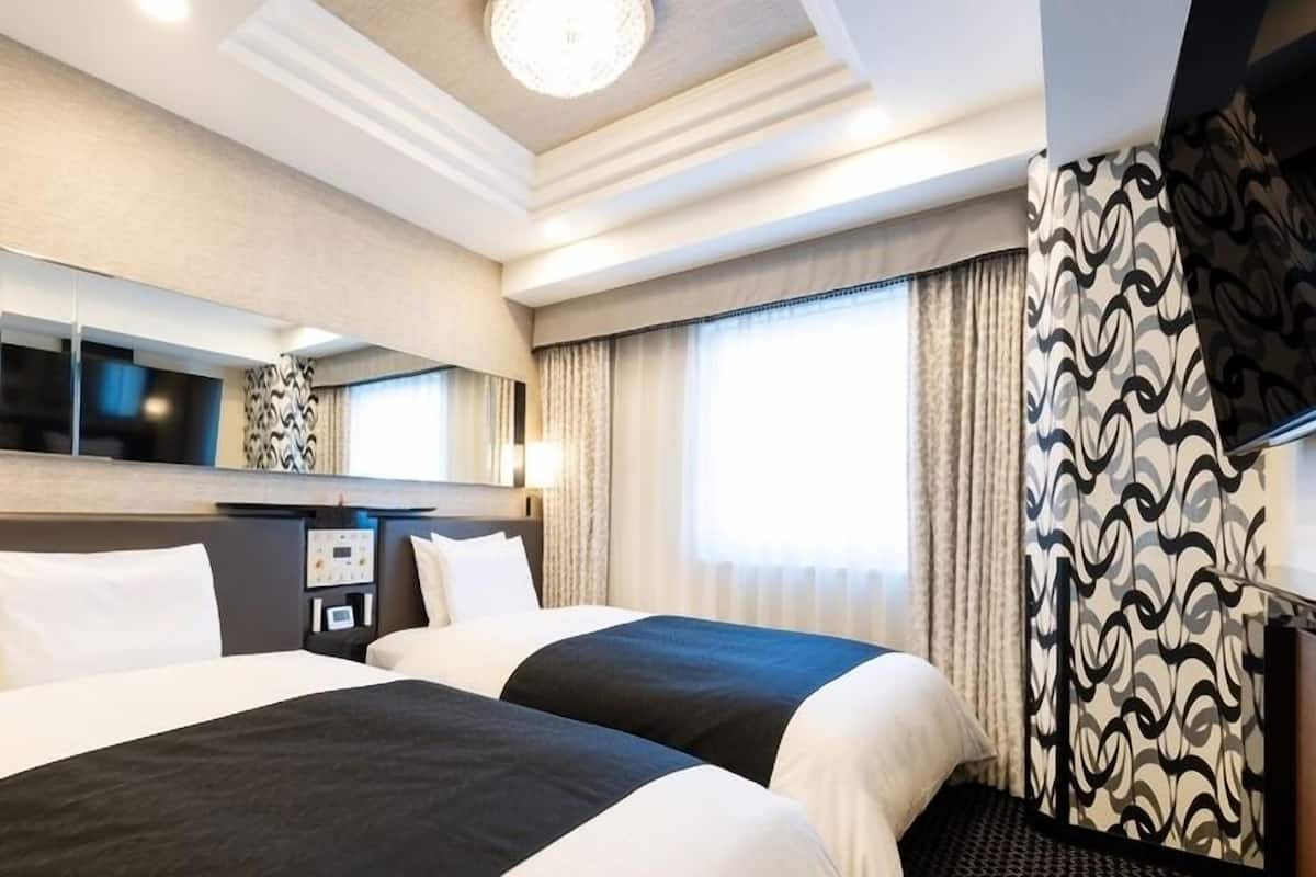 A hotel room with two beds, a large mirror, a flat-screen TV, and a window with curtains.