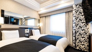 Een hotelkamer met twee bedden, een grote spiegel, een flatscreen televisie en een kamerbreed gordijn.