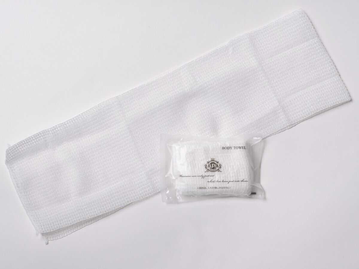 Une serviette blanche et un petit emballage en plastique portant la mention « SERVIETTE DE TOILETTE » ainsi qu’un logo et du texte.