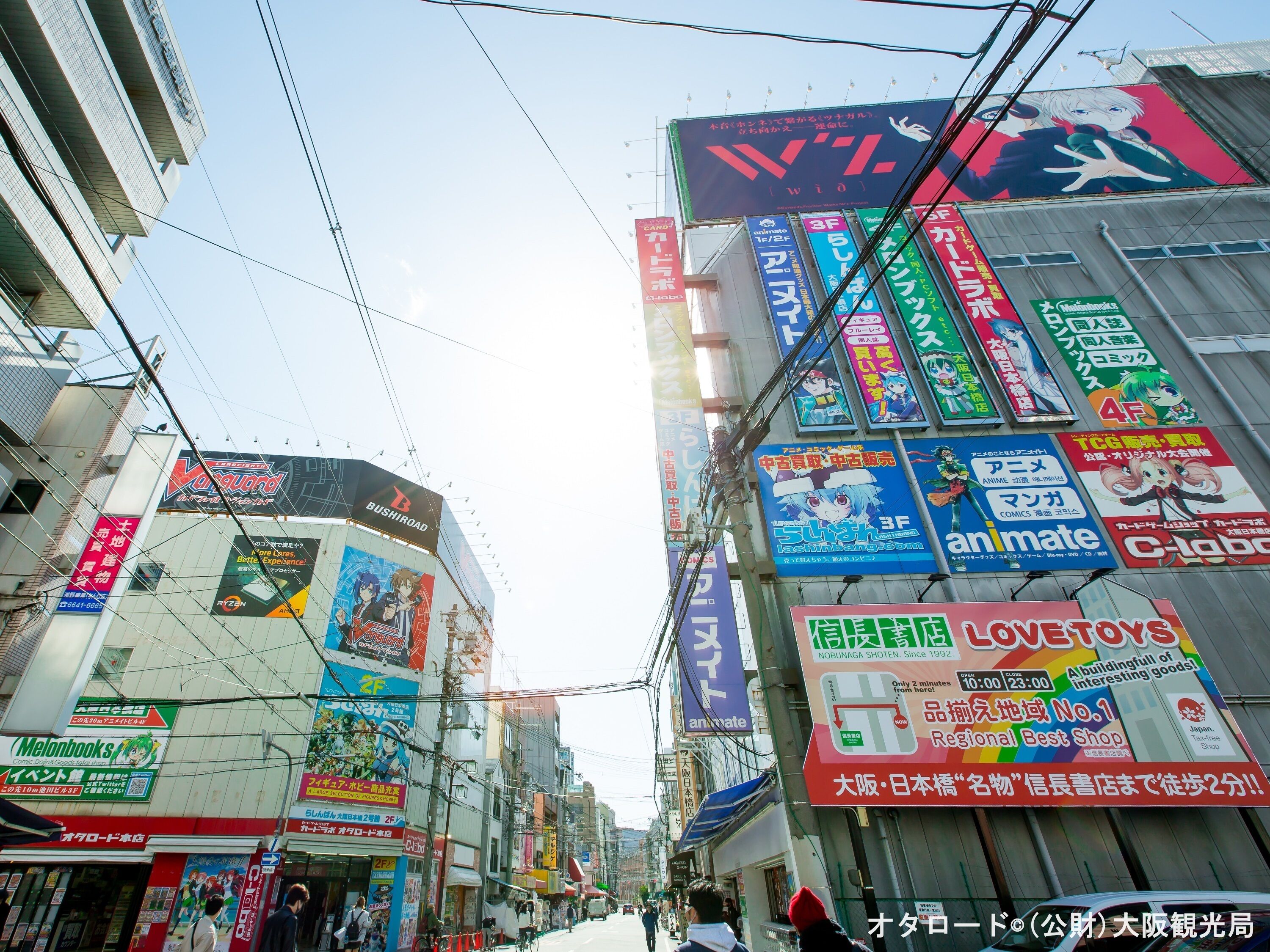 Una calle con varios edificios comerciales, incluyendo una tienda con un letrero grande de temática anime.