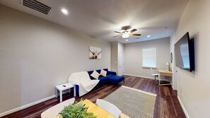 Relax in this stylish living room with a blue sofa, armchair, and large flat-screen TV.