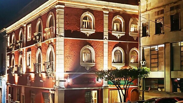 A historic building with arched windows and a red facade, likely a hotel or public building.