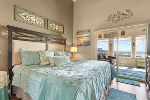 A bedroom with a bed, a nightstand, a lamp, and a view of a lake through the window.
