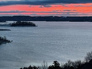 A calm lake with a small island in the foreground and a sunset sky in the background.