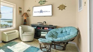 A living room with a view of a lake, a fireplace, a framed sign, and a chair. - Table Rock View Penthouse with Sun Room, Luxury Decor, Free Tickets & Prime Location (Branson)